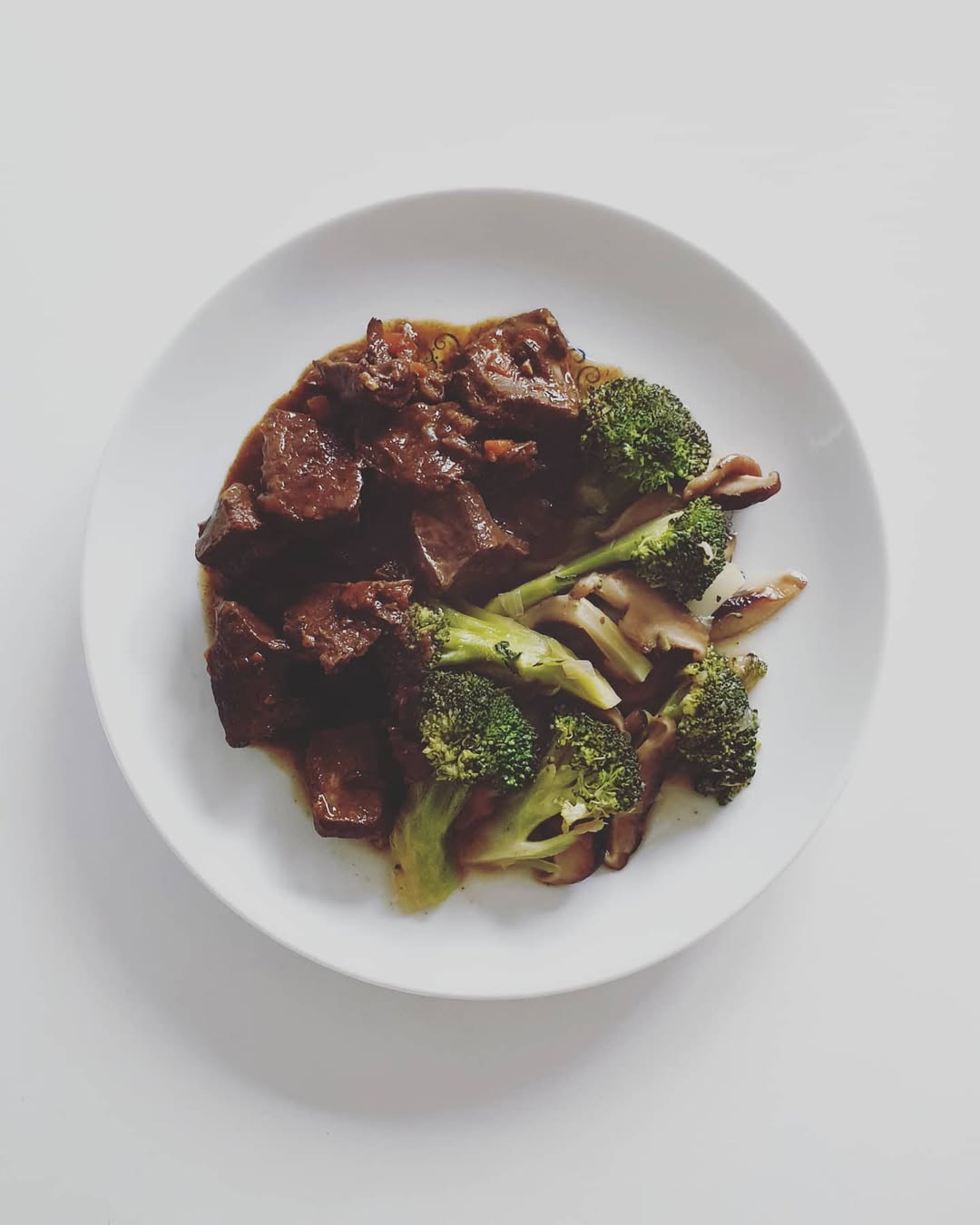 Plato de guiso de corazón con brócol al vapor y sofrito de cebolla, shiitake y ajo